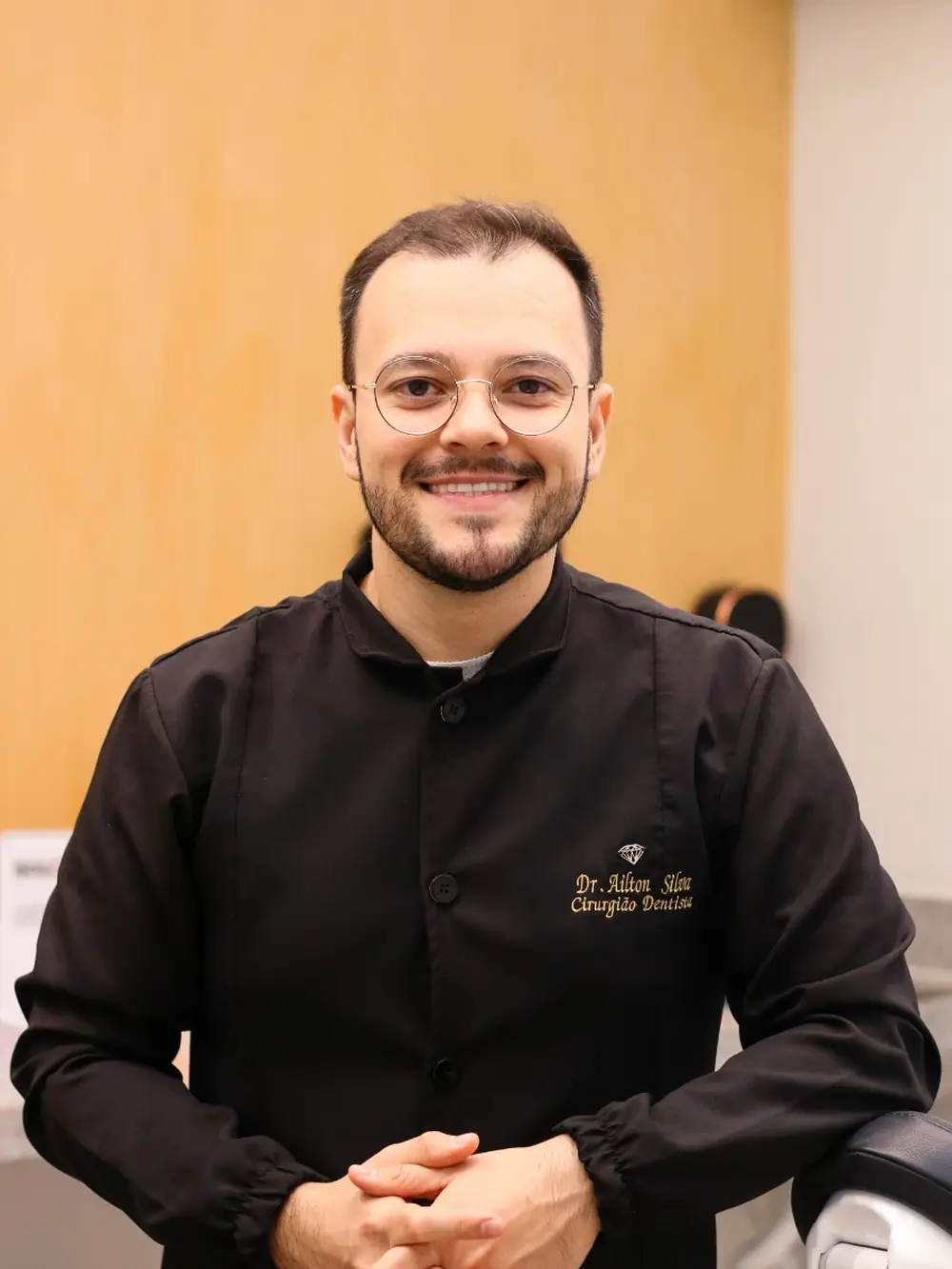 Dr. Ailton Silva, cirurgião-dentista da DS Odonto, sorrindo de jaleco preto